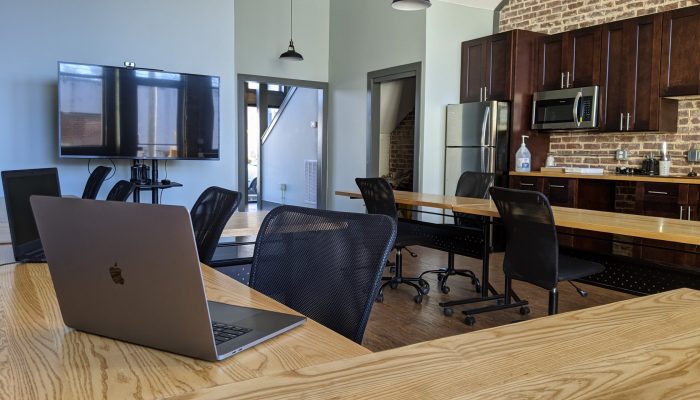 Sparta Workspace Picture of a coworking space with wooden tables, white walls, and a kitchenette.